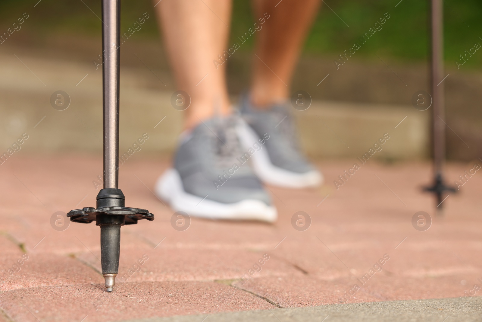 Photo of Man practicing Nordic walking with poles outdoors, selective focus