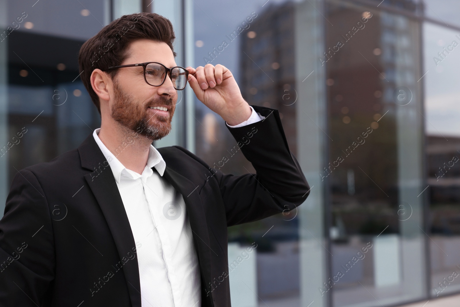 Photo of Smiling real estate agent in suit outdoors. Space for text