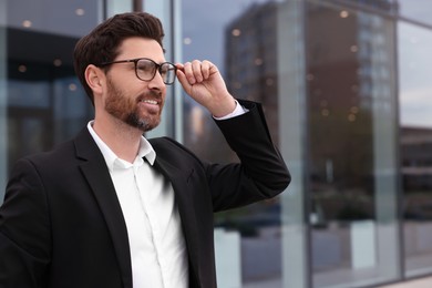 Photo of Smiling real estate agent in suit outdoors. Space for text