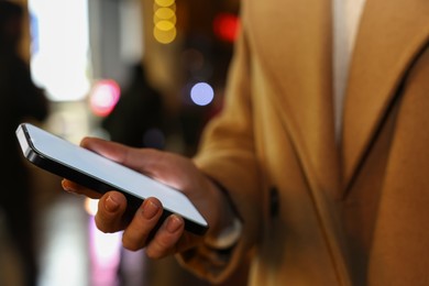 Photo of Woman with smartphone on night city street, closeup