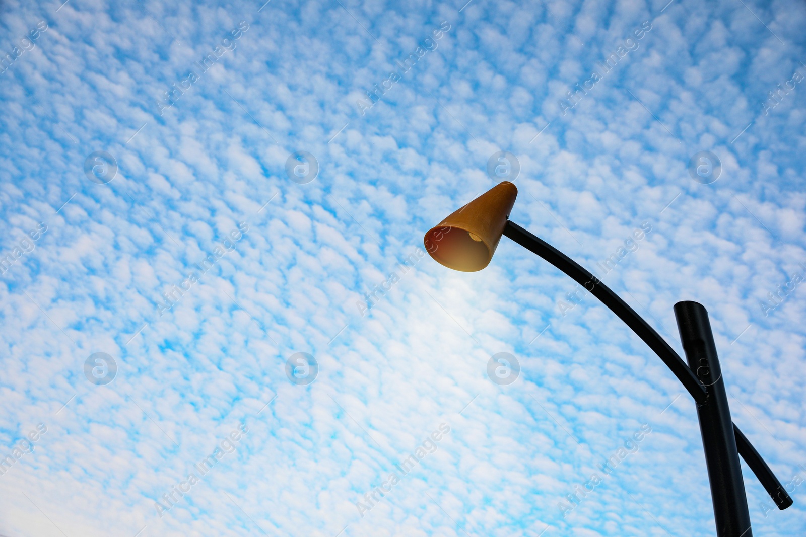 Photo of Street lamp against blue cloudy sky. Space for text