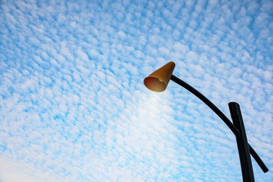 Photo of Street lamp against blue cloudy sky. Space for text