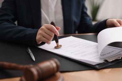 Photo of Notary sealing document at table in office, closeup