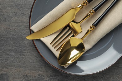 Elegant setting with golden cutlery on dark grey table, top view