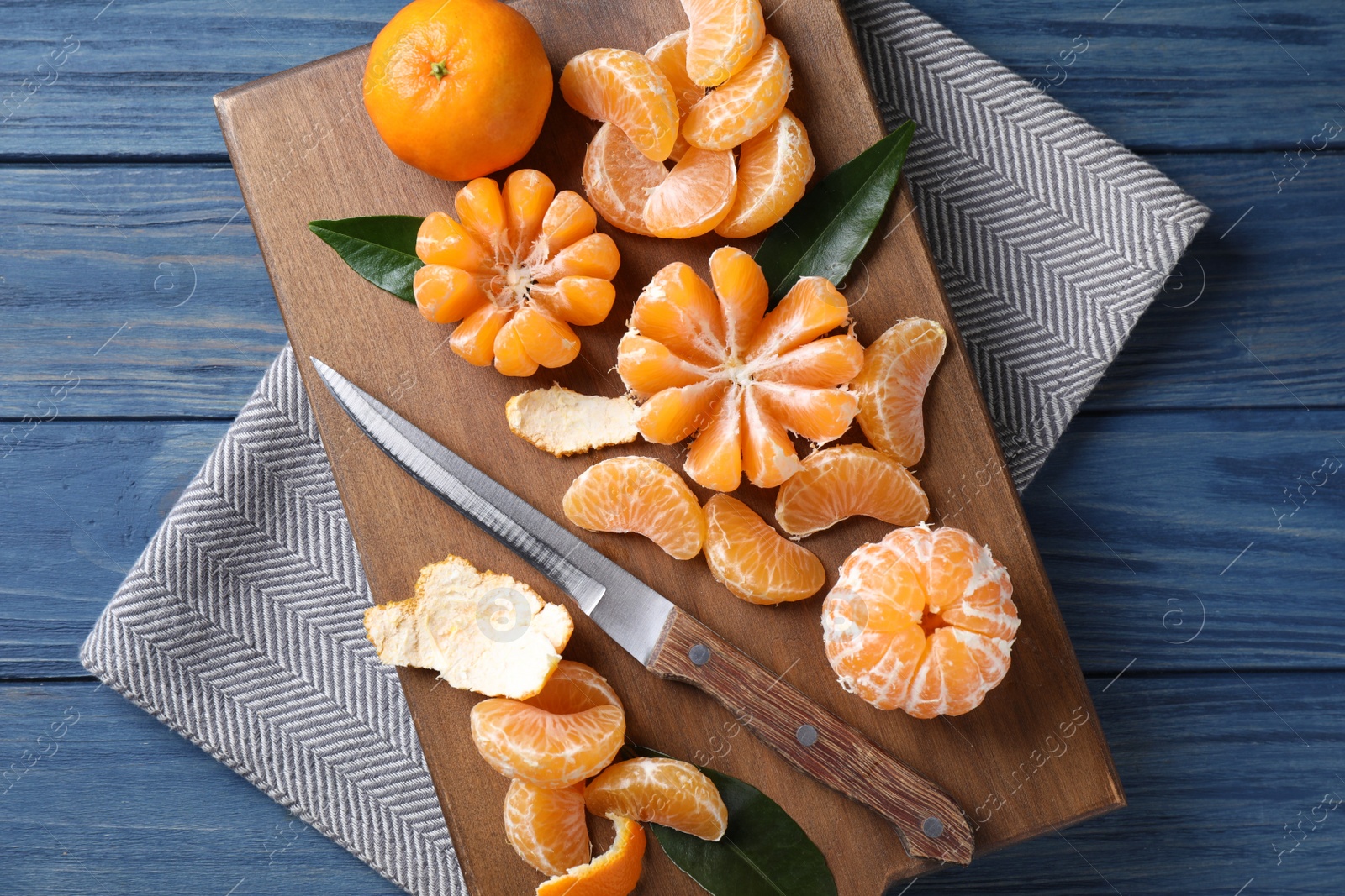 Photo of Fresh ripe tangerines on blue wooden table, top view