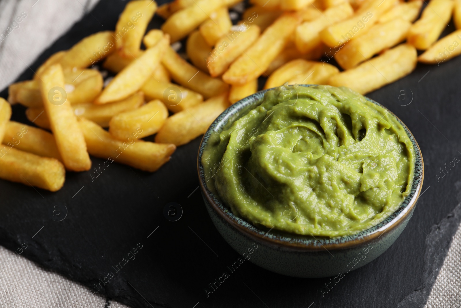 Photo of French fries and avocado dip on serving board, closeup