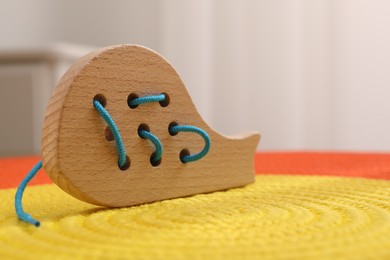 Photo of Motor skills development. Wooden lacing toy on color mat against light background, closeup. Space for text