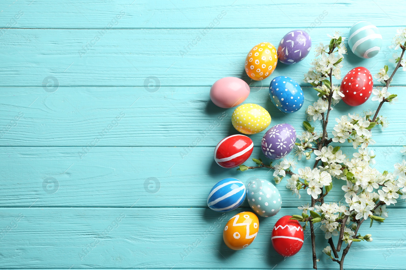 Photo of Flat lay composition with painted Easter eggs and blossoming branches on wooden background. Space for text