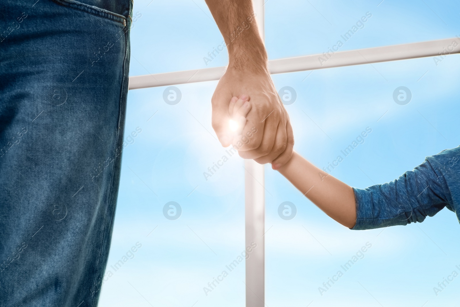 Photo of Father holding hands with his child indoors, closeup. Happy family