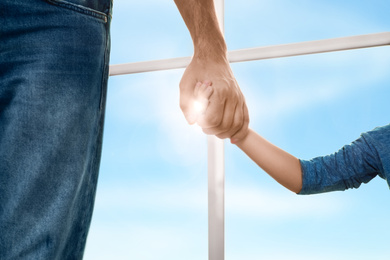 Father holding hands with his child indoors, closeup. Happy family