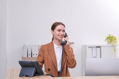 Female receptionist talking on phone at workplace