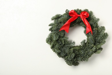 Christmas wreath made of fir tree branches with red ribbon on white background, space for text