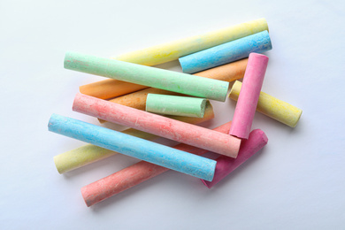 Color pieces of chalk on white background, top view
