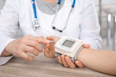 Doctor checking little boy's pulse with medical device in hospital, closeup