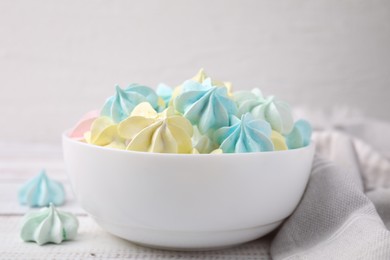 Photo of Tasty meringue cookies in bowl on white wooden table