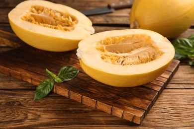 Photo of Halves of fresh spaghetti squash on wooden table. Cooking vegetarian dish