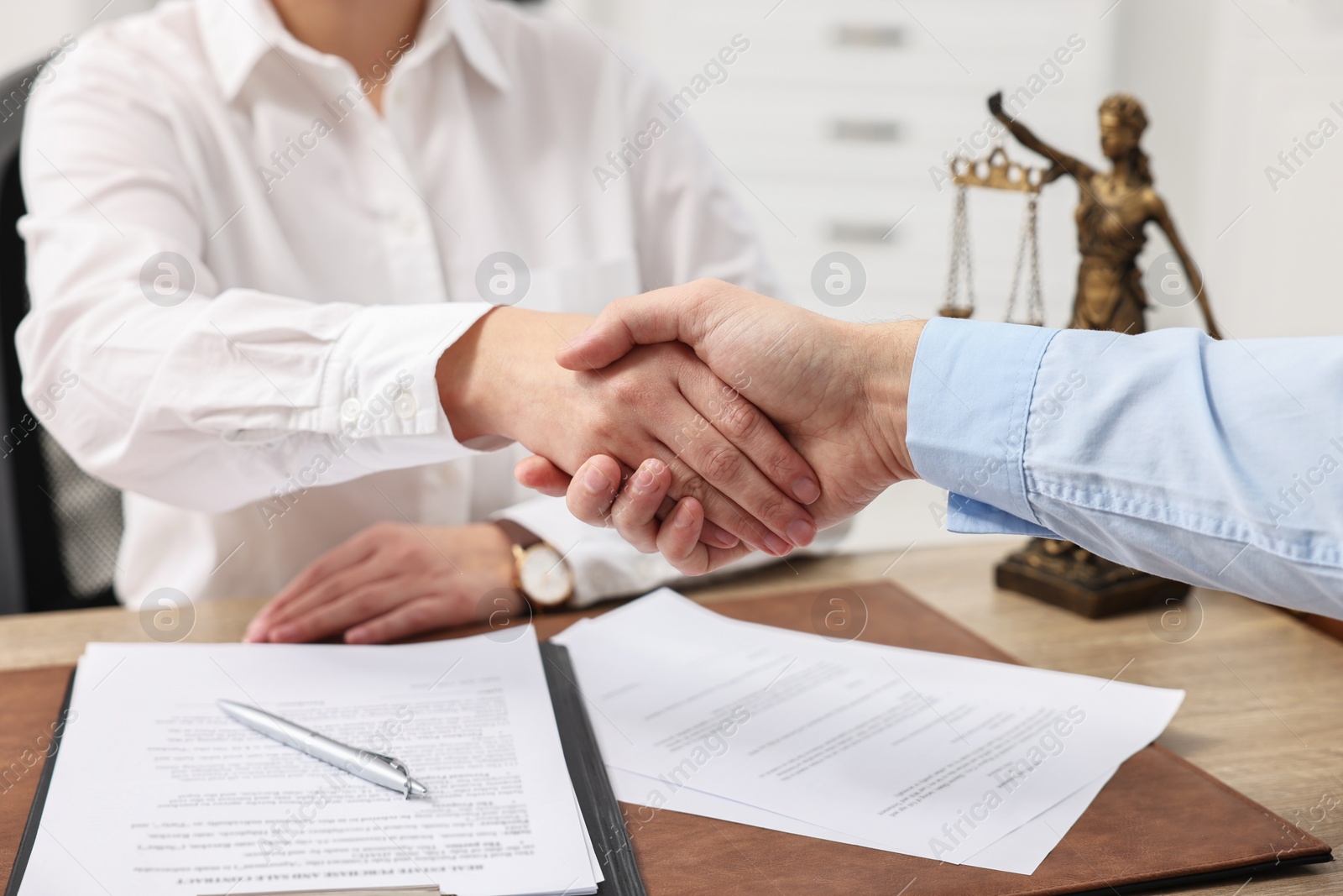 Photo of Lawyers shaking hands at table in office, closeup