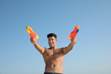 Man with water guns against blue sky