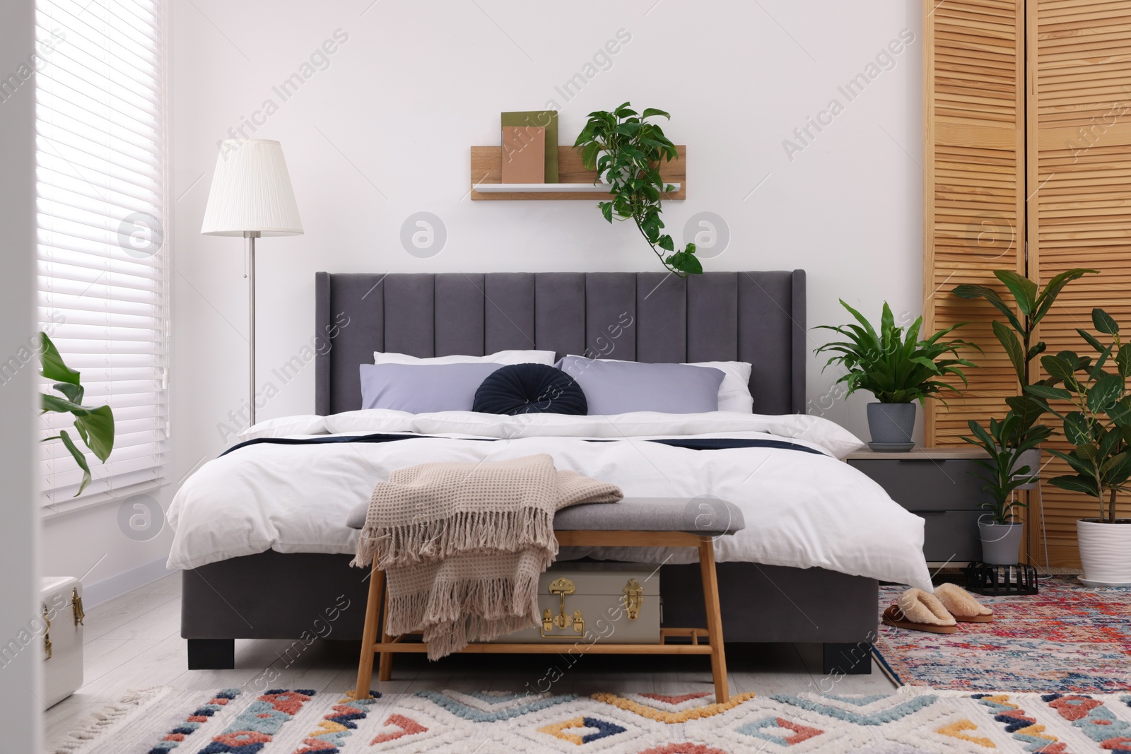 Photo of Stylish bedroom with double bed and beautiful green houseplants. Modern interior