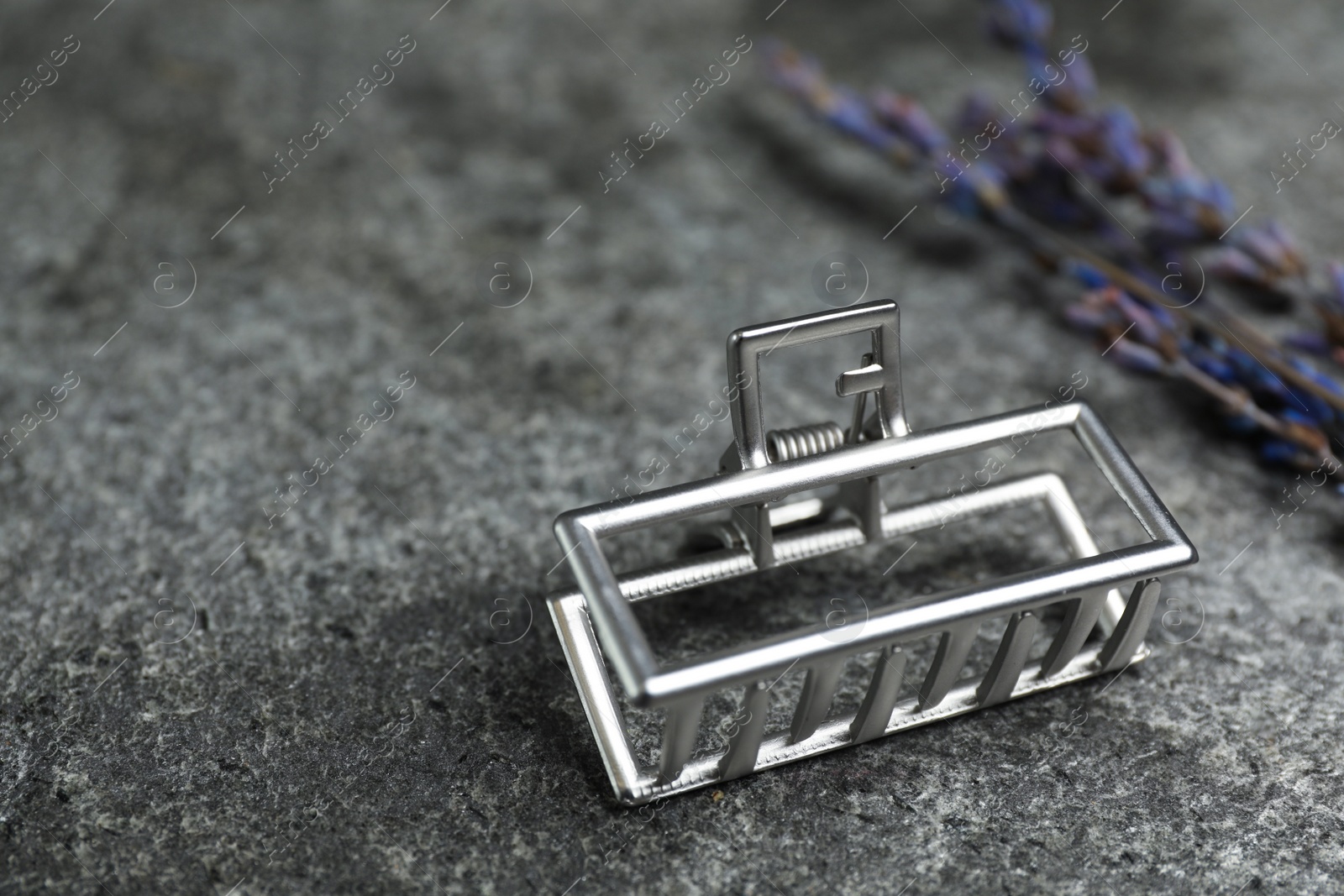 Photo of Beautiful silver hair claw and flowers on grey table. Space for text