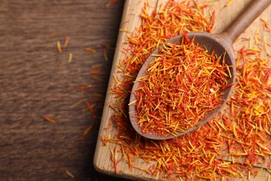 Aromatic saffron and spoon on wooden table, top view. Space for text