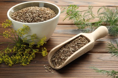 Photo of Scoop of dry seeds, bowl and fresh dill on wooden table