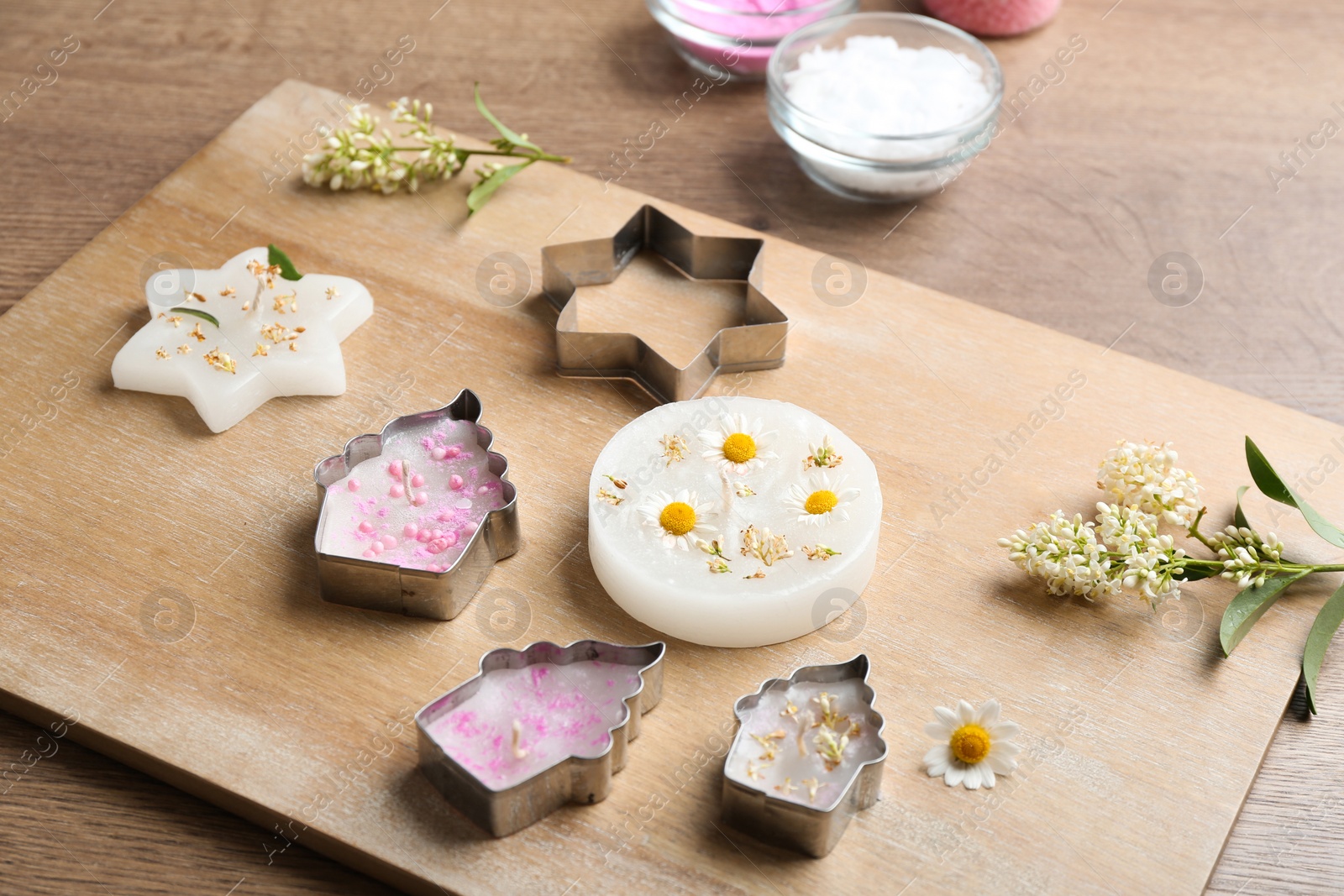 Photo of Different handmade candles and cutters on wooden background