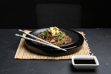 Photo of Stir-fry. Tasty noodles with meat and vegetables served on dark textured table