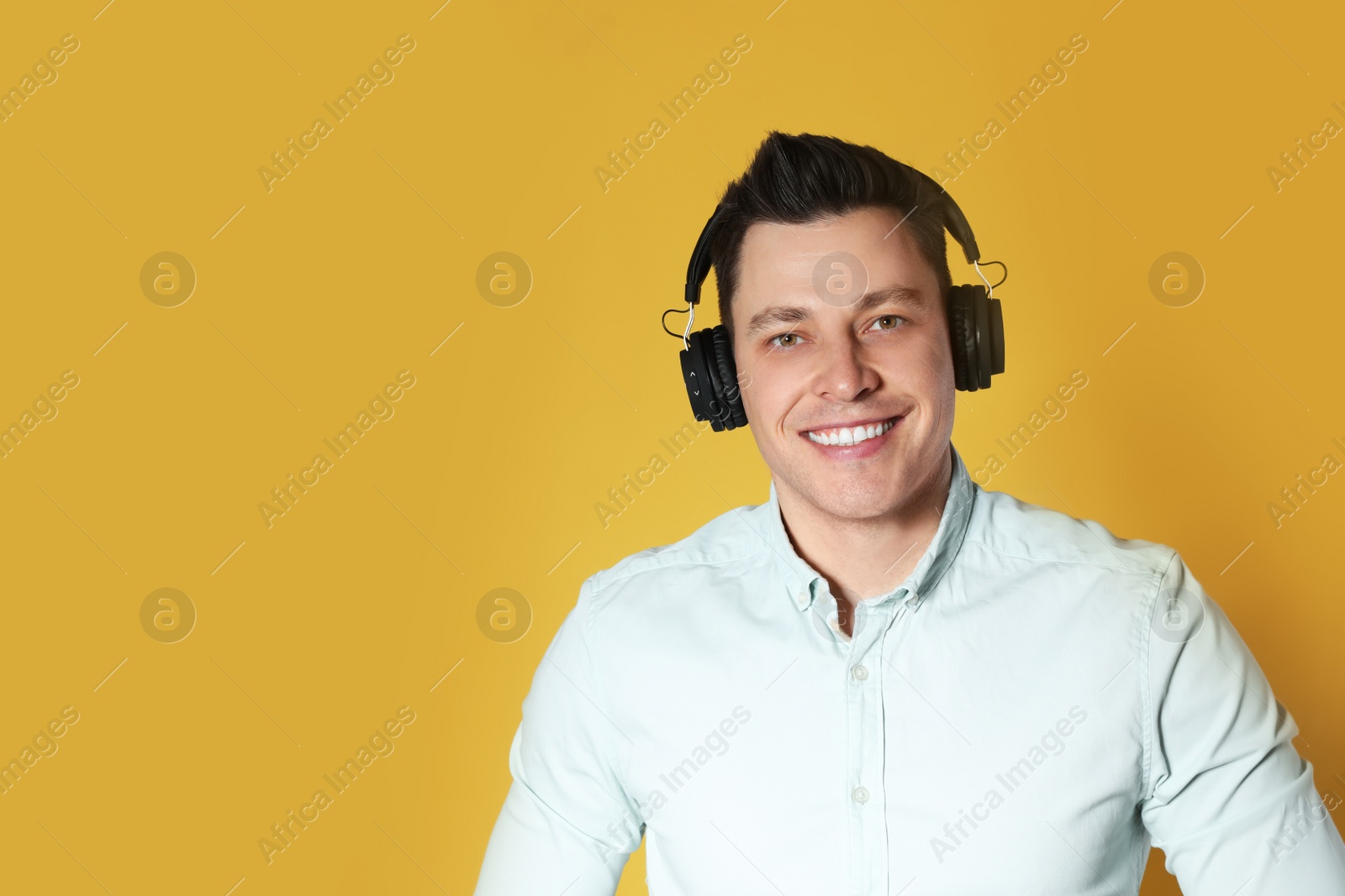 Photo of Man enjoying music in headphones on color background. Space for text