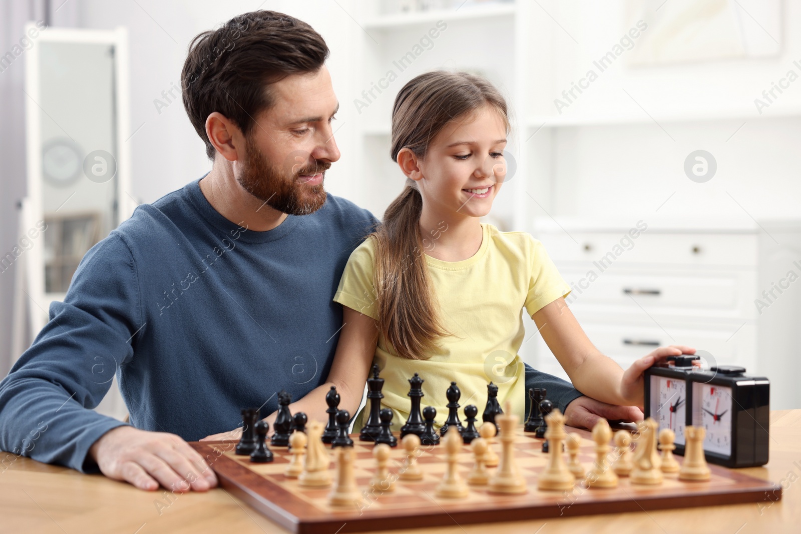 Photo of Father teaching his daughter to play chess at home