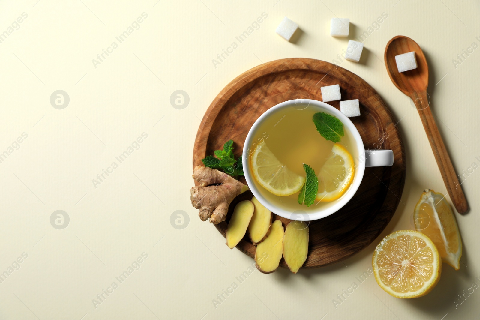 Photo of Delicious ginger tea and ingredients on beige background, flat lay. Space for text