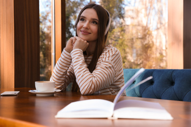 Woman listening to audiobook at table in cafe