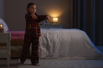 Girl in pajamas sleepwalking indoors at night