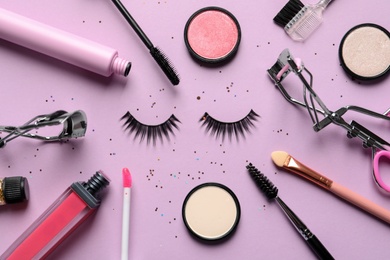 Photo of Flat lay composition with false eyelashes and other makeup products on pink background