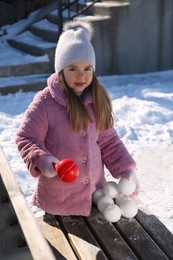 Photo of Cute little girl playing with snowball maker outdoors