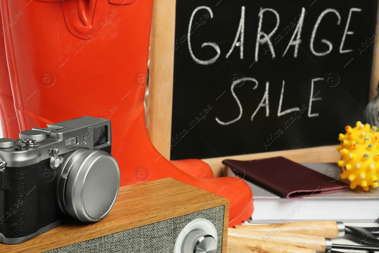 Photo of Sign Garage Sale written on blackboard near many different stuff, closeup