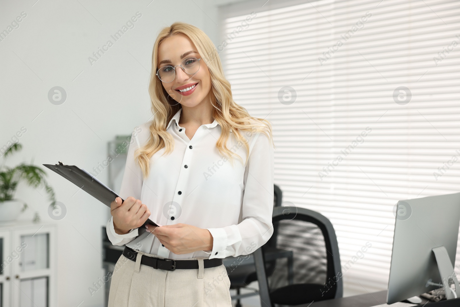 Photo of Happy secretary with glasses and clipboard in office, space for text