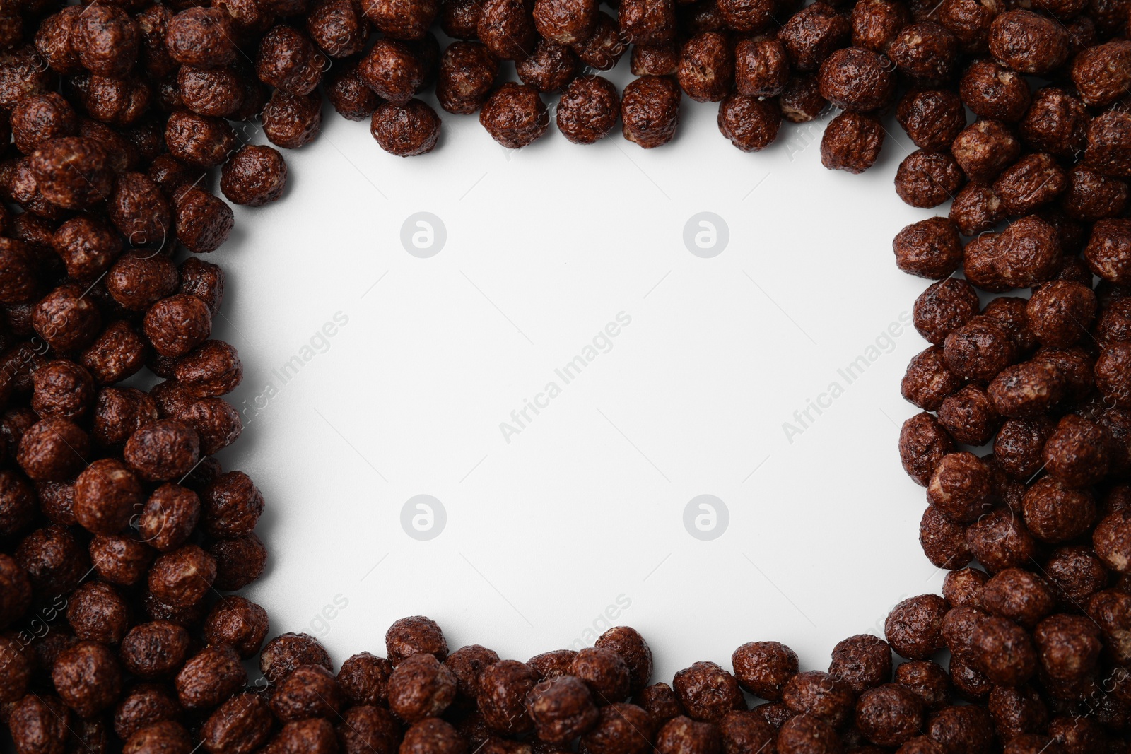 Photo of Frame made of chocolate cereal balls on white background, top view. Space for text