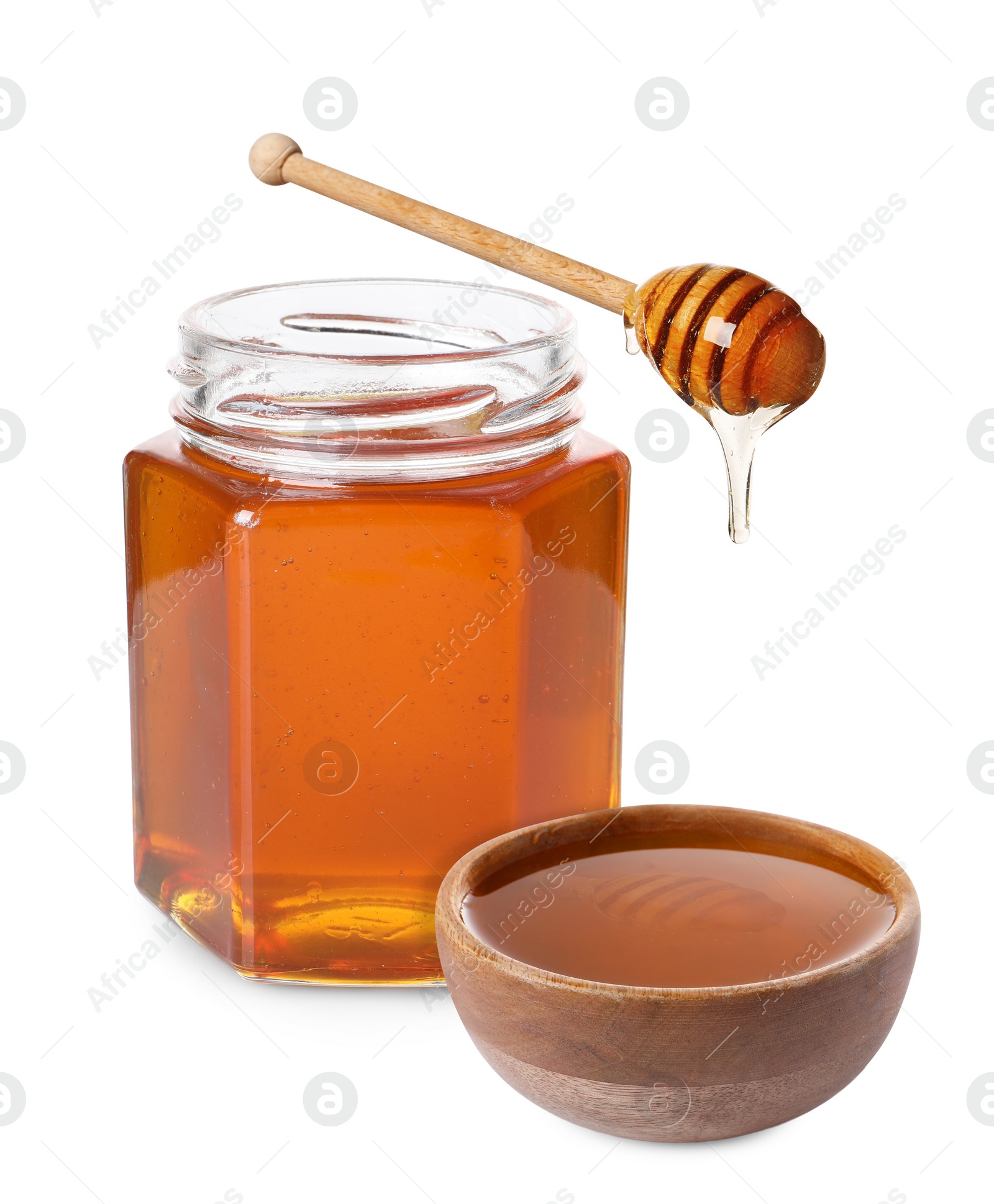 Image of Natural honey dripping from dipper into wooden bowl. Jar full of honey on white background