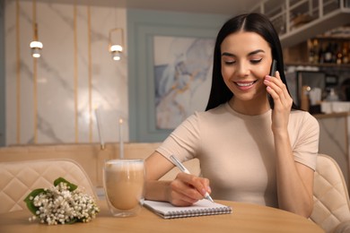 Photo of Woman with smartphone working at cafe in morning