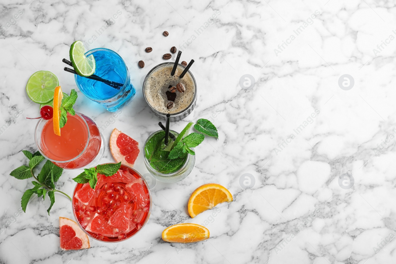 Photo of Flat lay composition with glasses of different tasty refreshing cocktails on marble background. Space for text