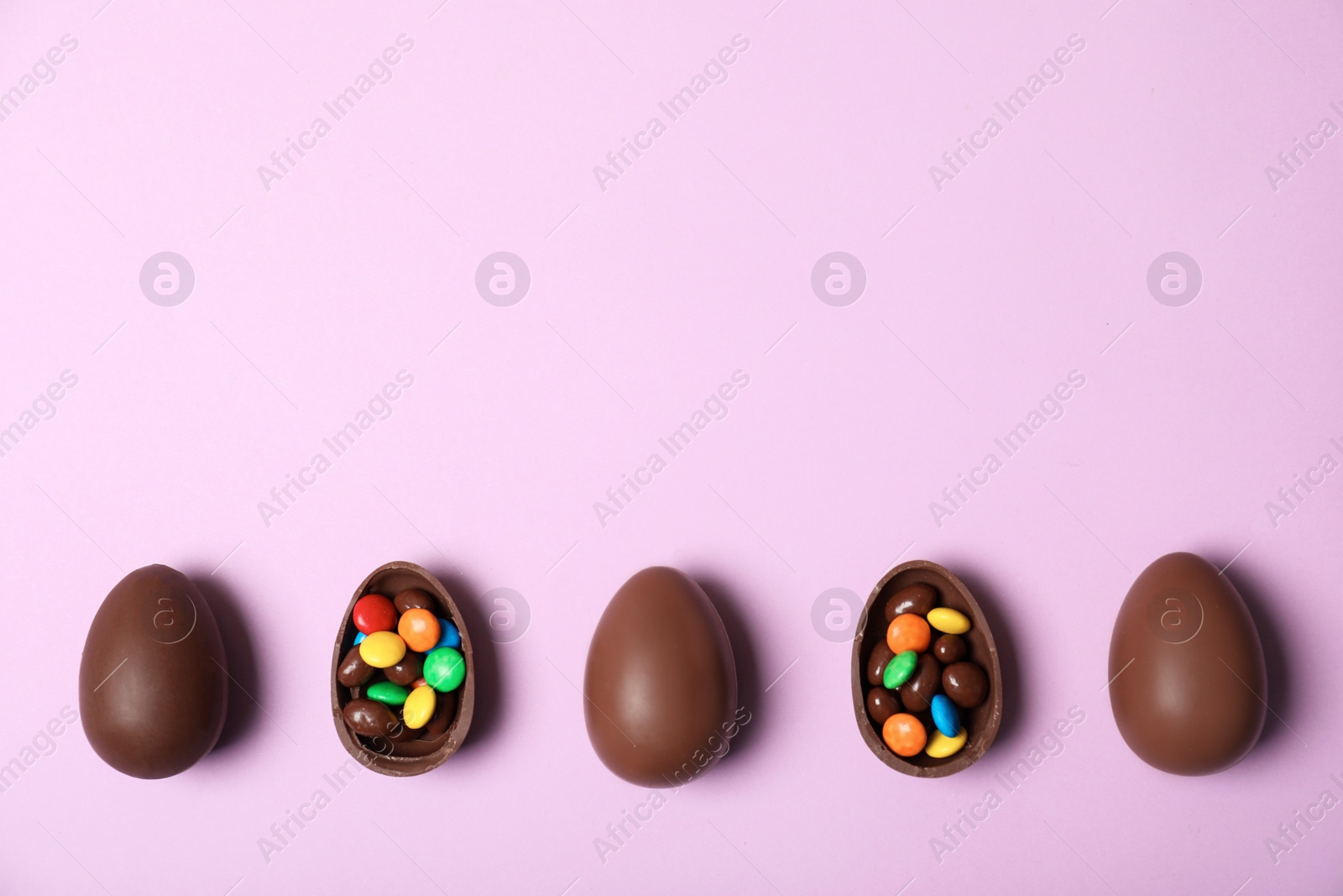 Photo of Flat lay composition with chocolate Easter eggs and space for text on color background