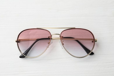 Photo of New stylish sunglasses on white wooden table, top view