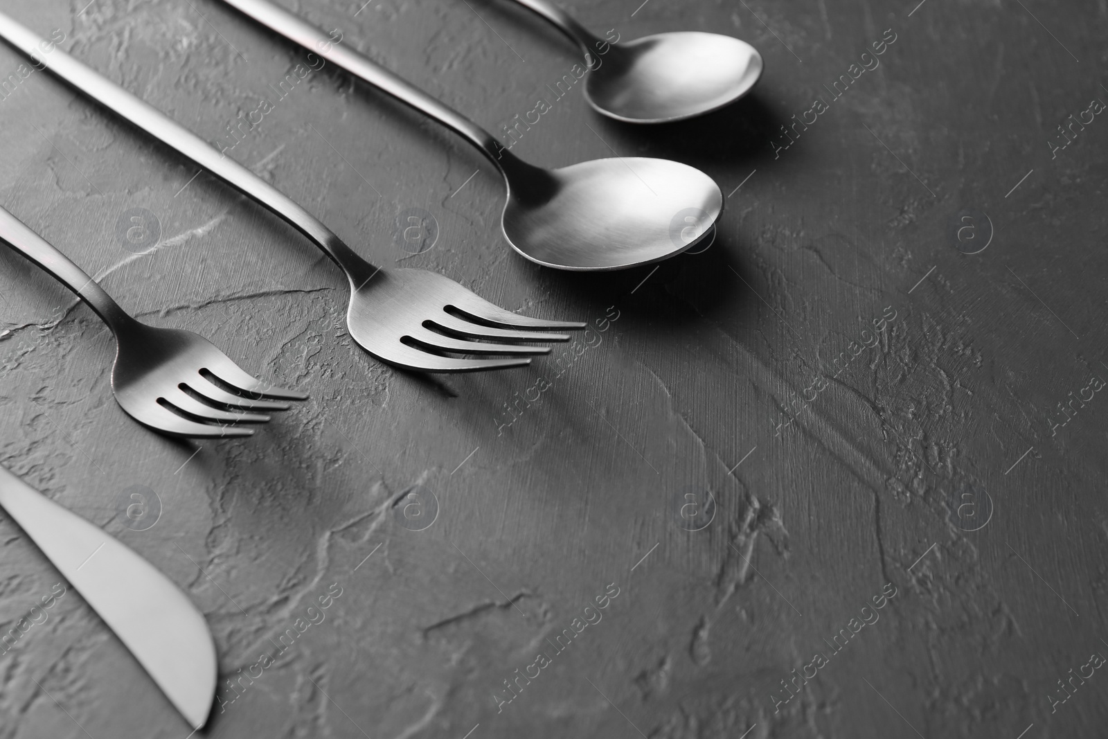 Photo of Beautiful cutlery set on black table, closeup. Space for text