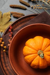 Photo of Autumn table setting with floral decor and pumpkin on dark grey background, flat lay