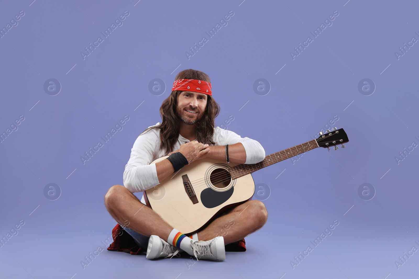 Photo of Stylish hippie man with guitar on violet background