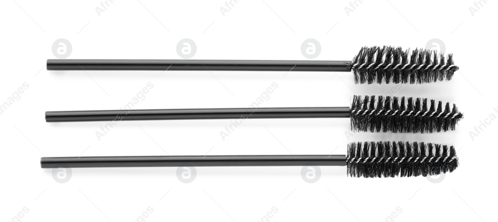 Photo of Three brushes for eyelashes on white background, top view