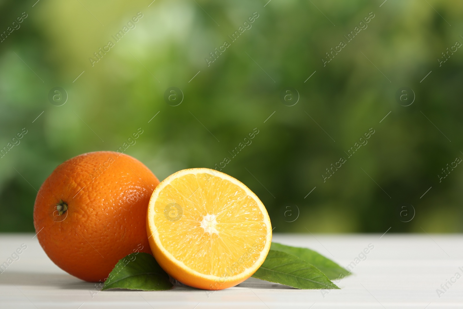 Photo of Fresh ripe oranges on white table against blurred background. Space for text