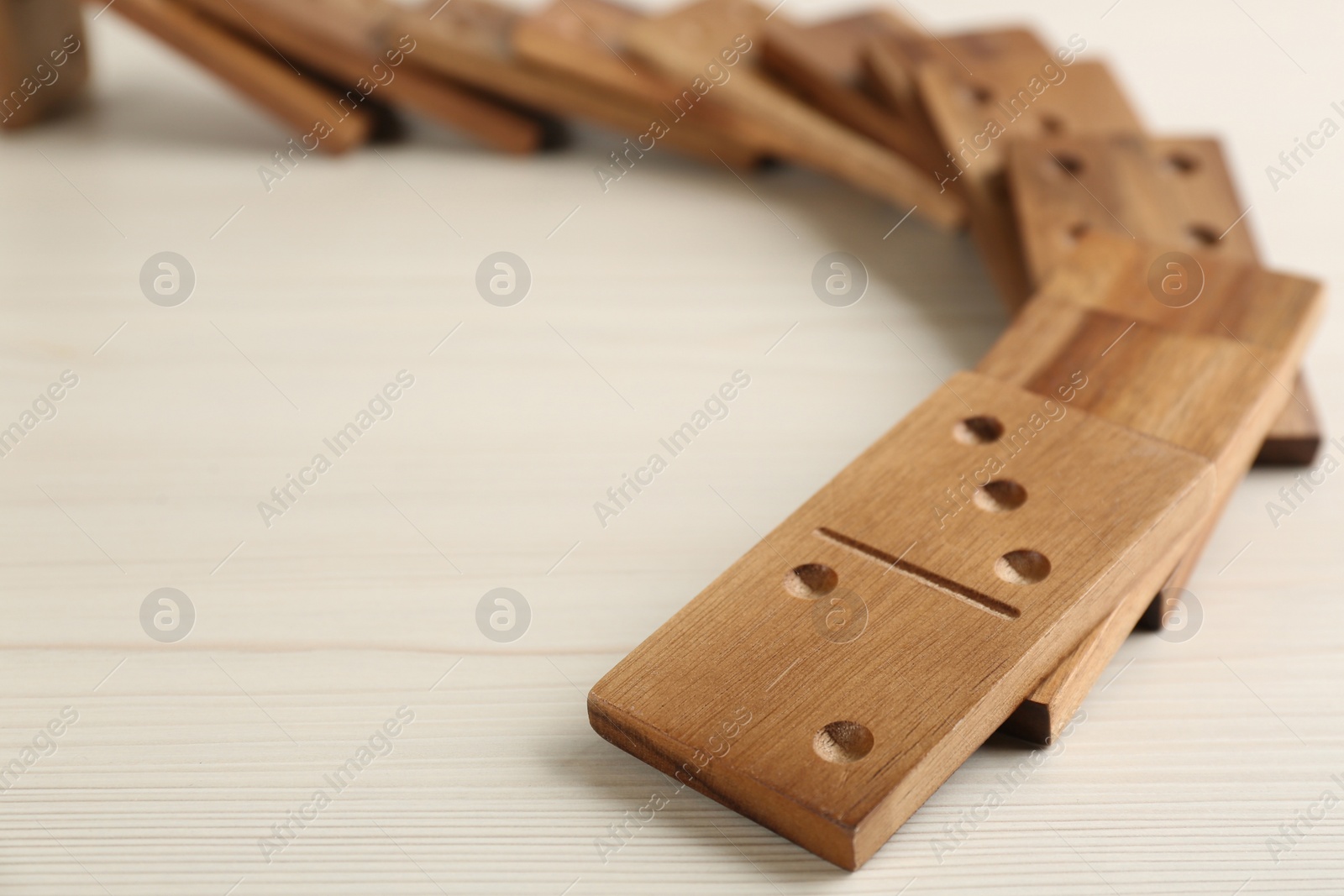 Photo of Fallen wooden domino tiles on white table, closeup