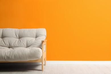 Photo of Stylish beige sofa near orange wall indoors, space for text. Interior design